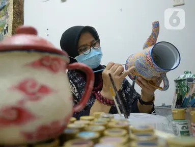 Perajin batik lukis ketel Nova Muhidir menyelesaikan lukisan batik di Studio Daroolang, Bintara, Tangerang Selatan, Banten, Rabu (2/12/2020). Lukisan ketel batik jadul khas nusantara di teko tempat air minum tersebut dijual dengan harga Rp 150 ribu hingga Rp 2,5 juta. (merdeka.com/Dwi Narwoko)