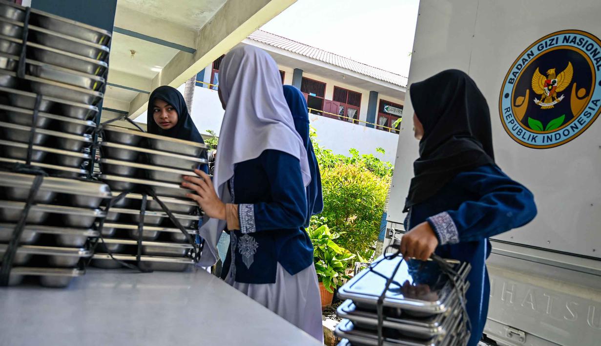 Para siswa mengambil nampan berisi makanan yang dipasok oleh program Makan Bergizi Gratis (MBG) di sebuah sekolah dasar di Banda Aceh pada Kamis 30 Oktober 2025. Program ini melibatkan berbagai pihak dan dilaksanakan secara bertahap. (CHAIDEER MAHYUDDIN/AFP)