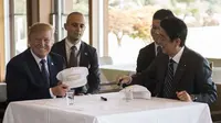 Donald Trump dan PM Abe saling tanda tangan topi golf dilanjutkan makan siang bersama (JIM WATSON / AFP)