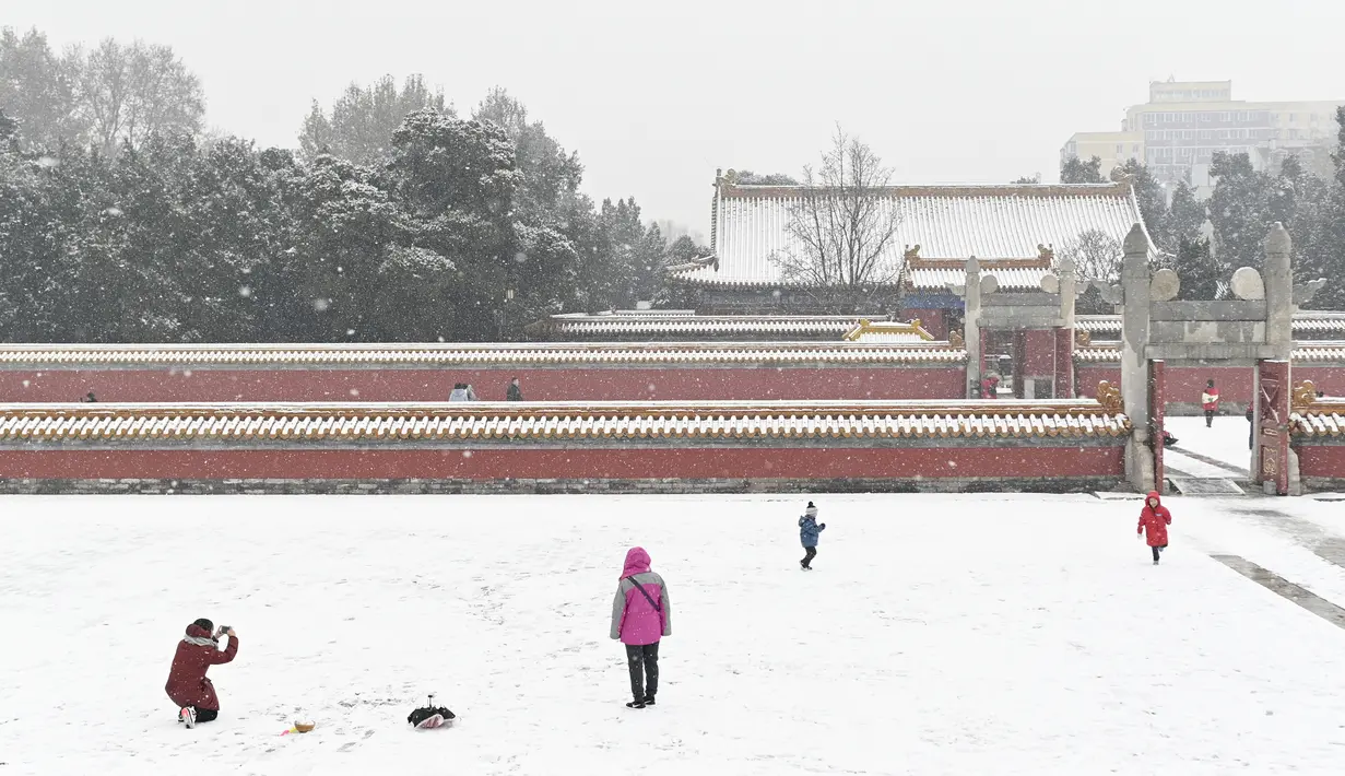 Orang-orang bermain ketika salju turun di sebuah taman di Beijing (16/12/2019). Beijing telah mengeluarkan peringatan untuk jalan-jalan es dan menyarankan warga untuk waspada terhadap gangguan lalu lintas, masalah kesehatan dan cuaca berangin setelah salju. (AFP Photo/Wang Zhao)