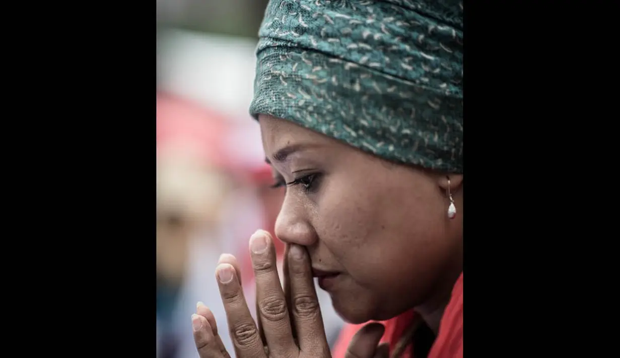 Seorang TKI tampak berdoa untuk rekannya yang dibunuh secara brutal oleh seorang bankir asal Inggris, Hong Kong, Minggu (9/11/2014). (AFP PHOTO/Philippe Lopez)
