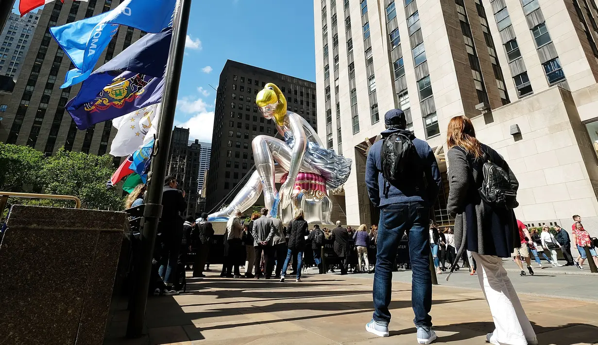 Sejumlah orang melihat balon penari balet karya seniman Jeff Koons, di Rockefeller Center, New York City, AS, Jumat (12/5). Keberadaan balon penari balet menjadi ajang foto pengunjung Rockefeller Center. (Spencer Platt / Getty Images / AFP)
