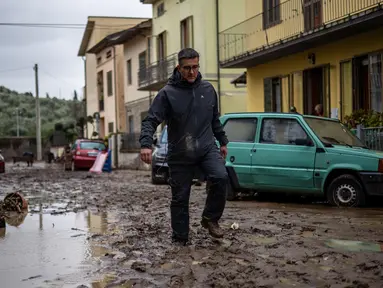 Seorang pria berjalan di lumpur di Montemurlo setelah hujan deras, pada 3 November 2023. (Federico SCOPPA/AFP)