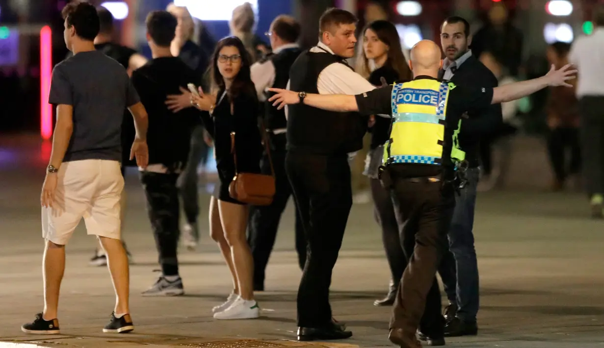Seorang anggota polisi berusaha menjauhkan orang-orang dari London Bridge, setelah dua serangan teror di pusat kota London, Sabtu (3/6). Serangan brutal terjadi di London Bridge dan Borough Market, yang dilakukan lima orang pria. (AP Photo/ Matt Dunham)