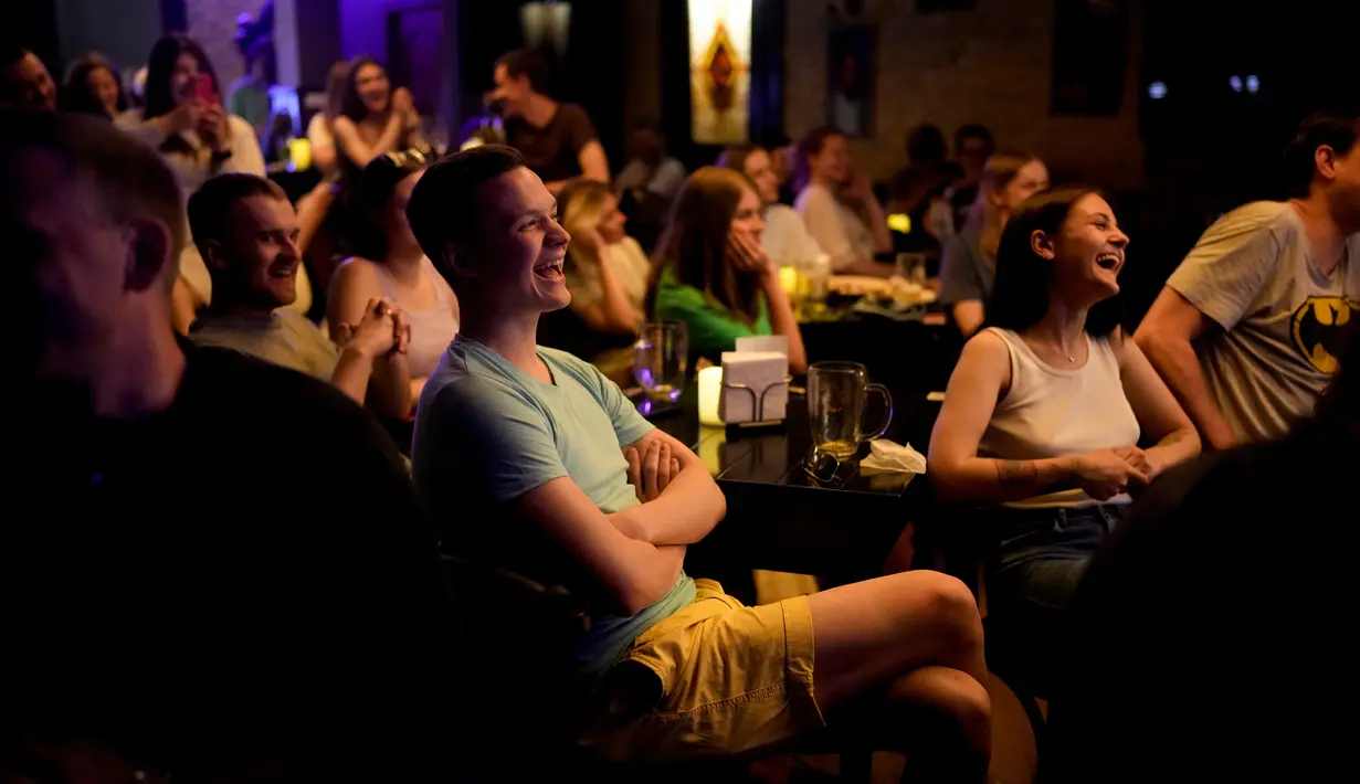 Orang-orang menghadiri pertunjukan stand-up comedy Serhiy Lipko di Kyiv, Ukraina, 11 Juni 2022. Perang Ukraina tidak terlalu lucu, tetapi orang-orang di sana belajar menertawakan kengerian itu semua untuk tetap waras dalam konflik yang telah menewaskan puluhan ribu orang tersebut. (AP Photo/Natacha Pisarenko)
