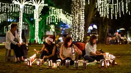 Keluarga dikelilingi lilin selama Hari Lilin Kecil di Cali, Kolombia (7/12). Selama perayaan Immaculate Conception of the Virgin Mary, orang menyalakan lilin di rumah mereka dan di lampu jalan di Kolombia. (AFP Photo/Luis Robayo)