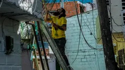 Seorang pria mengecat dinding bangunan di kawasan kumuh El Pesebre, pinggiran kota Medellin, Kolombia, 19 Juni 2017. Seniman Prancis, Tarik Bouanani melukis 230 rumah di kawasan tersebut membentuk mural raksasa. (JOAQUIN SARMIENTO/AFP)