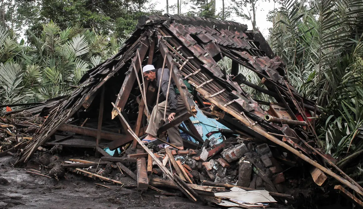 Badan Nasional Penanggulangan Bencana (BNPB) mengimbau masyarakat untuk tidak beraktivitas dalam radius 8 km dari puncak dan 20 km di sepanjang aliran Besuk Kobokan untuk menghindari korban jiwa. Tampak dalam foto, seorang pria mencari barang-barang yang bisa diselamatkan di dalam rumahnya yang hancur akibat aliran piroklastik selama letusan Gunung Semeru di Desa Supiturang, Lumajang, Jawa Timur pada Kamis 20 November 2025. (Agus Harianto/AFP)
