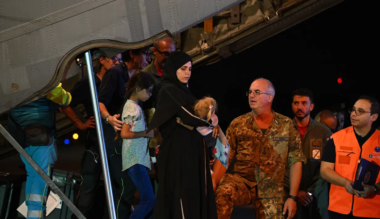 Petugas medis dan tenaga kesehatan menyambut anak-anak Palestina dari Gaza beserta keluarga mereka, setelah pesawat militer Italia C130J dari Israel mendarat pada 14 Agustus 2025 di Bandara Ciampino, Roma. (Andreas SOLARO/AFP)