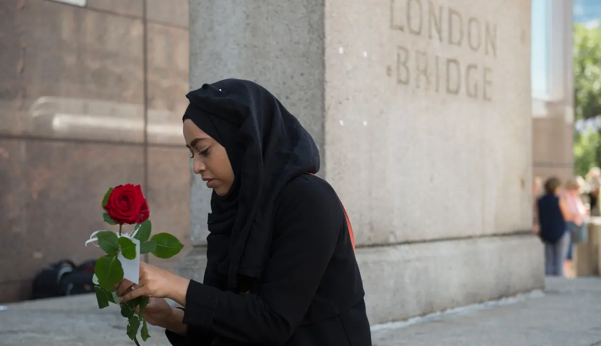 Seorang muslim bersiap membagikan bunga mawar kepada pejalan kaki di London Bridge, Minggu (11/6). Ribuan bunga mawar yang dibagikan sebagai solidaritas atas serangan teror London itu merupakan hasil donasi para warga Muslim. (David Mirzoeff/PA via AP)