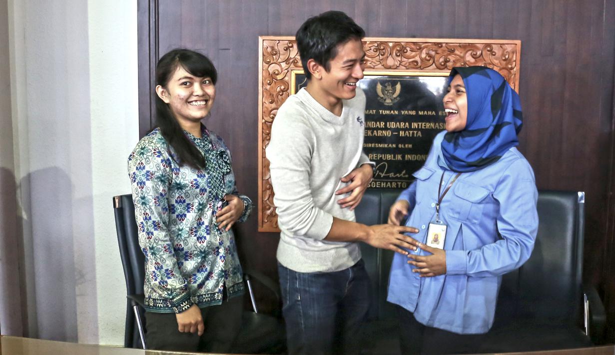 Pebalap Nasional, Rio Haryanto saat mengelus perut seorang ibu, yang sedang hamil saat foto bersama di Bandara Soekarno-Hatta, Cengkareng, Tangerang, Rabu (2/11/2015). (Bola.com/Nicklas Hanoatubun)