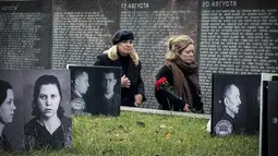 Orang-orang mengunjungi tugu peringatan bagi para korban represi politik di Butovo, di luar Moskow, pada Kamis 30 Oktober 2025, menandai hari peringatan. Peringatan ini sebagai pengingat akan kejahatan rezim Soviet dan penghormatan bagi para korban tewas dalam teror politik. Acara peringatan ini melibatkan keluarga dan kerabat korban yang berziarah ke lokasi tersebut. (Nikita BORISSOV/AFP)