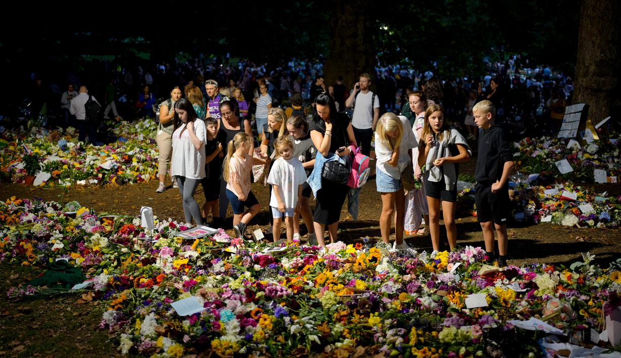 Orang-orang berkumpul di depan karangan bunga untuk Ratu Elizabeth II di Green Park, dekat Istana Buckingham di London, Senin (12/9/2022). Elizabeth juga sempat bertugas selama Perang Dunia II sebagai mekanik selagi menjabat sebagai kepala negara. (AP Photo/Markus Schreiber)