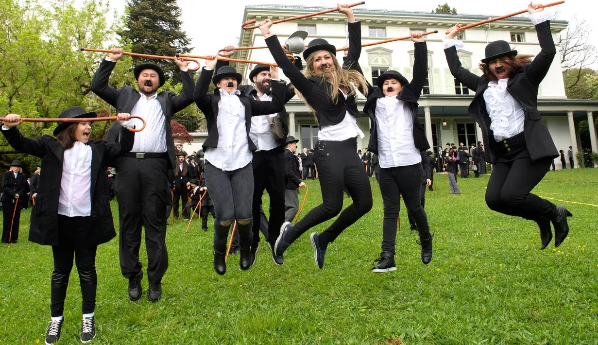 Sejumlah penggemar berpakaian Charlie Chaplin berpose saat menggelar pertemuan yang dihadiri 662 orang di Corsier sur Vevey, Swiss, Minggu (16/4). Tak hanya menjiplak gaya Charlie Chaplin, mereka juga menirukan tingkah konyolnya. (Richard Juilliart/AFP)