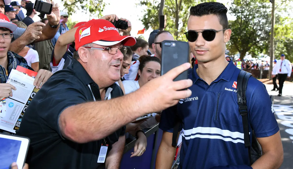 Pembalap anyar Sauber, Pascal Wehrlein melakukan selfie dengan seorang penggemar menjelang sesi latihan bebas pertama di Grand Prix Australia, Melbourne, Jumat (24/3). (AFP Photo/WILLIAM WEST)