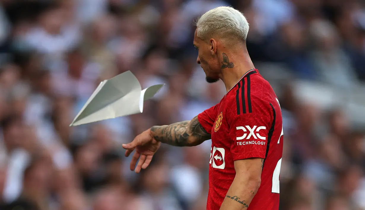 Pemain Manchester United, Antony memungut pesawat kertas yang dilemparkan penonton ke dalam lapangan pada laga pekan kedua Liga Inggris 2023/2024 melawan Tottenham Hotspur di Tottenham Hotspur Stadium, London, Inggris, Minggu (20/08/2023) WIB. (AFP/Adrian Dennis)