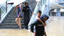 Petugas polisi menggendong seorang anak saat menyusuri sebuah jalan yang tergenang banjir di Kota Jishou, Prefektur Otonom Etnis Tujia dan Miao Xiangxi, Provinsi Hunan, China tengah (8/7/2020). Hujan lebat mengguyur sejumlah daerah di Xiangxi pada Rabu (8/7) pagi waktu setempat. (Xinhua/Liu Zhenjun)