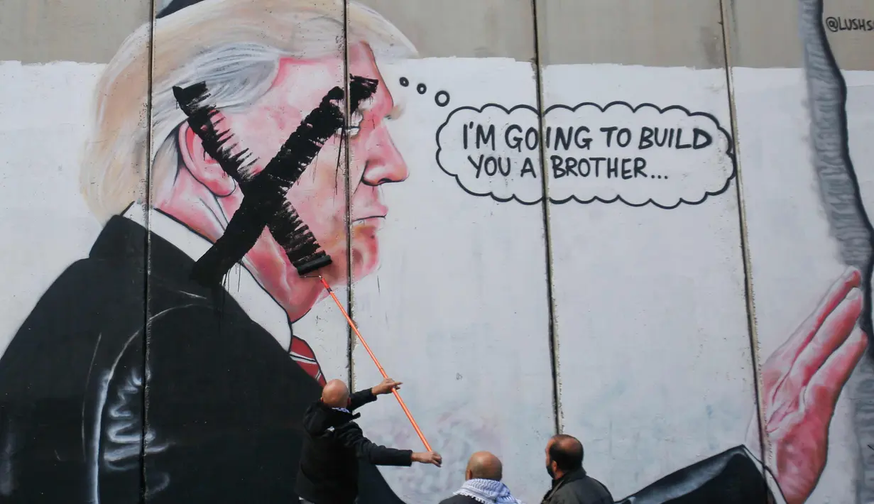 Warga Palestina menyoret wajah Presiden AS, Donald Trump saat demonstrasi di kota Bethlehem, Tepi Barat, (7/12). (AP Photo/Nasser Shiyoukhi)
