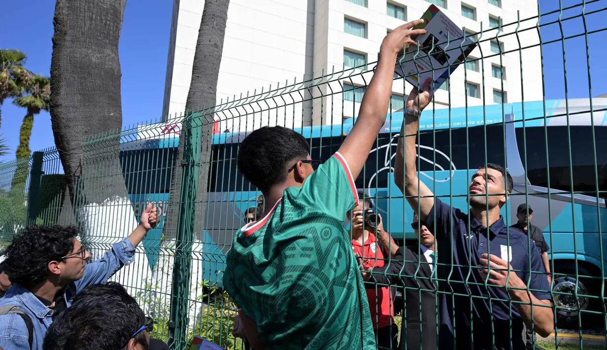 Pemain depan Iran, Mehdi Taremi, menerima album stiker Piala Dunia Panini dari penggemar di luar Hotel Marriott sebelum berangkat untuk sesi latihan di Tijuana, Meksiko, pada 10 Juni 2026, menjelang turnamen sepak bola Piala Dunia FIFA 2026. (Guillermo Arias/AFP)