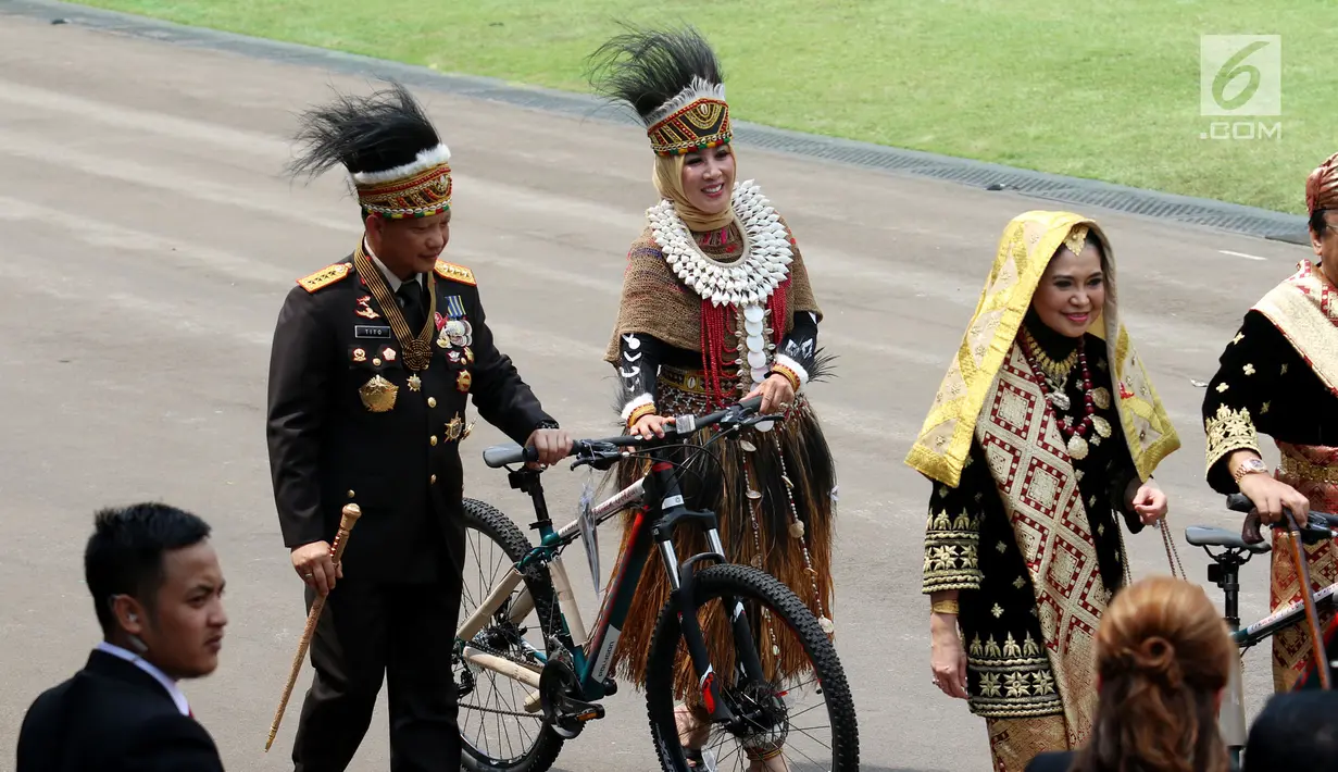 Kapolri Jendral Tito Karnavian bersama istri Tri Suswati mengenakan pakaian adat Papua membawa hadiah sepeda dari Presiden Jokowi usai peringatan HUT RI ke 72 di Istana Merdeka, Jakarta, Kamis (17/8). (Liputan6.com/Pool)