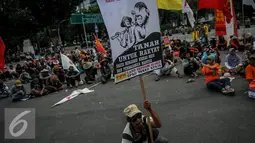 Seorang pengunjuk rasa membawa sebuah poster saat aksi di depan Istana Merdeka, Jakarta, Senin (26/9). Mereka meminta Pemerintah untuk merealisasikan  pelaksanaan reformasi agraria. (Liputan6.com/Faizal Fanani)