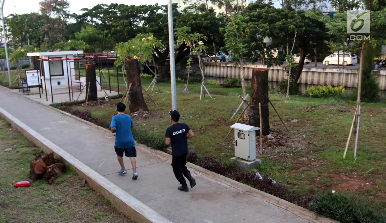 Warga melintas di samping pohon-pohon Sudirman yang dipindah ke kawasan RTH Kalijodo, Jakarta Utara, Kamis (15/3). Sebanyak delapan pohon jenis mahoni di Sudirman telah dipindahkan ke Taman Kalijodo. (Liputan6.com/Arya Manggala)