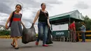 Seorang ibu dan anaknya membawa bahan makanan yang dibeli di Kolombia, berjalan pulang menuju perbatasan di kota Cucuta, Rabu (6/7). Sejumlah warga Venezuela mencari makanan dengan menerobos perbatasan masuk ke wilayah Kolombia. (Schneyder MENDOZA/AFP)