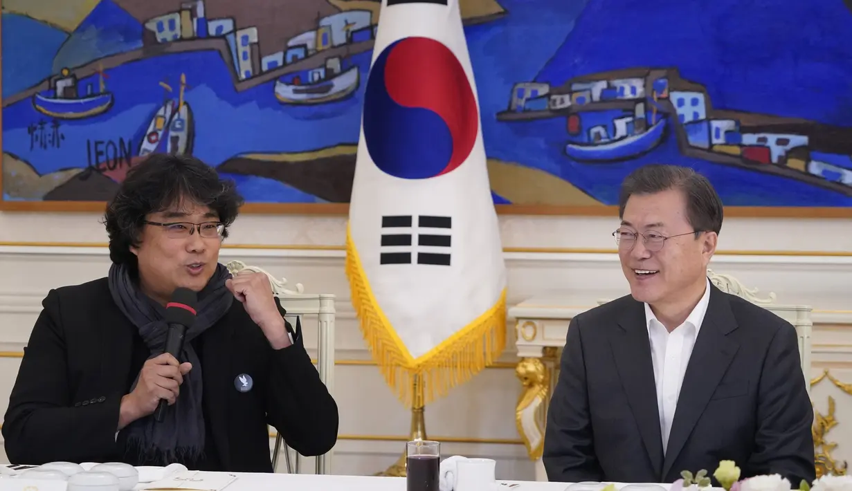Sutradara Bong Joon Ho berbicara di sebelah Presiden Korea Selatan Moon Jae-in saat makan siang di Blue House, Seoul, Kamis (20/2/2020). Presiden Moon mengundang Sutradara Bong Joon Ho dan seluruh tim untuk merayakan kemenangan Parasite yang membawa pulang empat Piala Oscar 2020. (KIM HONG-JI/AFP)