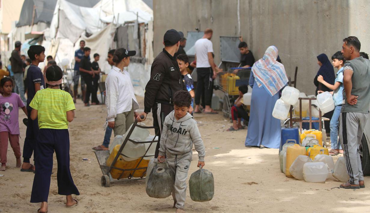 Warga Palestina yang mengungsi mengumpulkan air minum untuk dibawa kembali ke tempat penampungan mereka setelah rumah mereka hancur akibat bombardir Israel, di kamp pengungsi Bureij, Jalur Gaza Tengah pada Senin 18 Mei 2026. (Eyad Baba/AFP)
