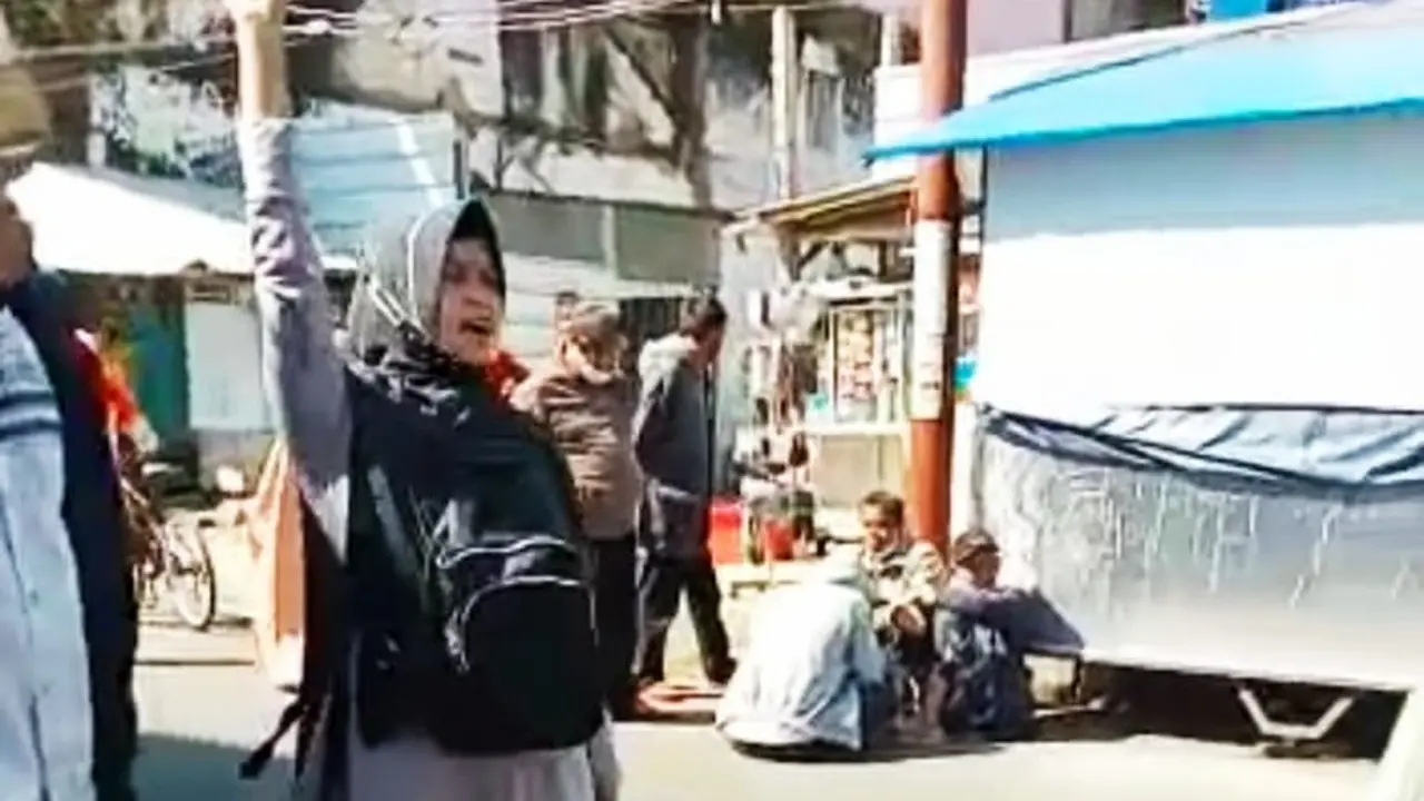 Salah seorang emak-emak PKL Pengkolan Garut, Jawa Barat mengacungkan tangan tanda penolakan pelaksanaan PPKM Darurat yang dinilai memberatkan bagi para PKL untuk berjualan.