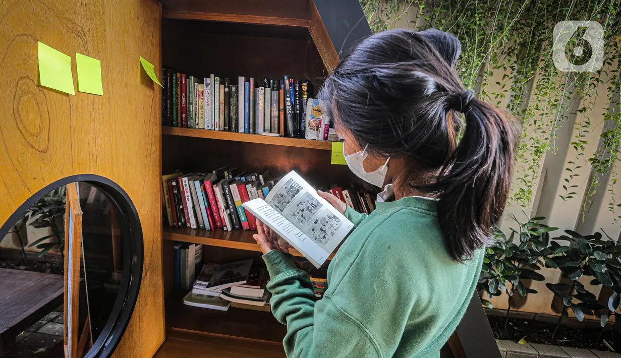Warga membaca buku dekat perpustakaan bersama Bookhive Jakarta di kawasan Taman Situ Lembang, Jakarta, Selasa (27/4/2021). Warga bisa meminjam dan menyumbang buku pada rak terbuka Bookhive Jakarta. (Liputan6.com/Faizal Fanani)