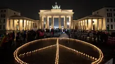 Para aktivis meletakkan lilin yang membentuk tanda perdamaian di depan Gerbang Brandenburg, menjelang peringatan satu tahun invasi Rusia ke Ukraina, di Berlin, Jerman, Kamis (23/2). Setahun sudah invasi Rusia ke Ukraina berlangsung. Namun, hingga kini belum ada tanda-tanda Rusia ingin mengakhiri agresi dan berdamai. (Paul Zinken/dpa via AP)