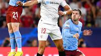 Pemain Manchester City Sergio Gomez (kiri) dan Jack Grealish (kanan) berebut bola dengan pemain Sevilla Rafa Mir pada pertandingan sepak bola grup G Liga Champions di Seville, Spanyol, 6 September 2022. Manchester City menang 4-0. (AP Photo/Jose Breton)