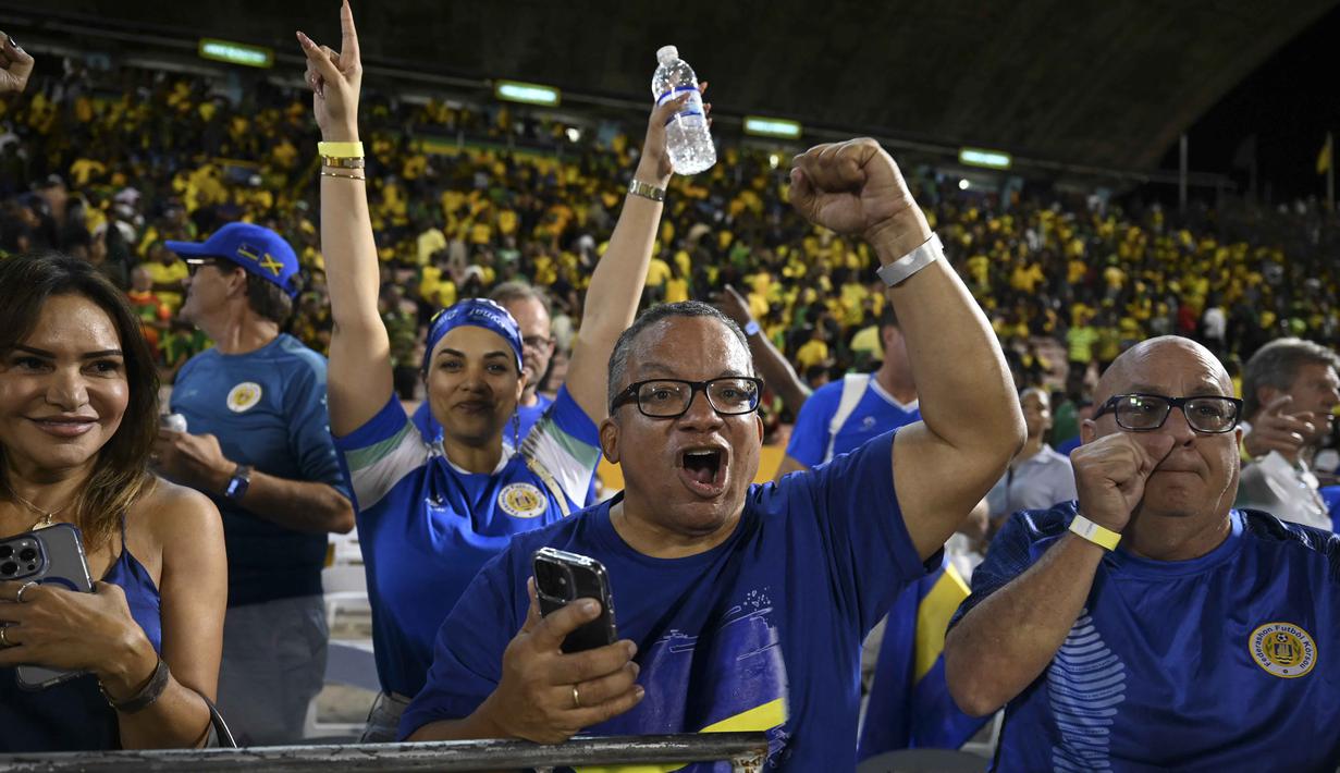 Dengan capaian tersebut, untuk pertama kalinya dalam sejarah sepak bola mereka, Timnas Curacao memastikan diri tampil di Piala Dunia. Tampak dalam foto, suporter Timnas Curacao merayakan hasil imbang melawan Jamaika pada Grup B Kualifikasi Piala Dunia 2026 zona CONCACAF di Independence Park Stadium, Jamaika pada 18 November 2025. (Ricardo MAKYN/AFP)