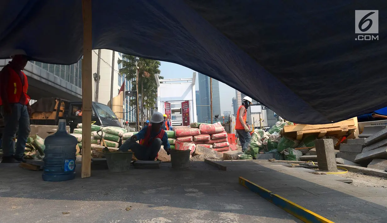 Pekerja menyelesaikan proyek pembangunan trotoar di Jalan MH Thamrin,Jakarta,Kamis (19/7). Penataan di trotoar di Jalan Sudirman - MH Thamrin ditargetkan selesai akhir Juli 2018. (Merdeka.com/Imam Buhori)