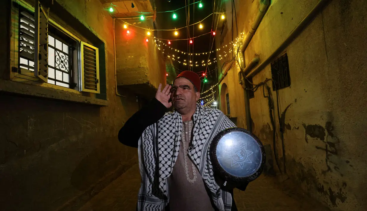 Nizar al-Dabbas Palestina berusia lima puluh tahun, seorang "Musaharati" yang memainkan peran tradisional sebagai "penabuh drum Ramadhan", membangunkan umat Islam untuk makan sahur sebelum fajar selama bulan suci Ramadhan di Khan Yunis di Jalur Gaza selatan (5/4/2022). (AFP/Said Khatib)