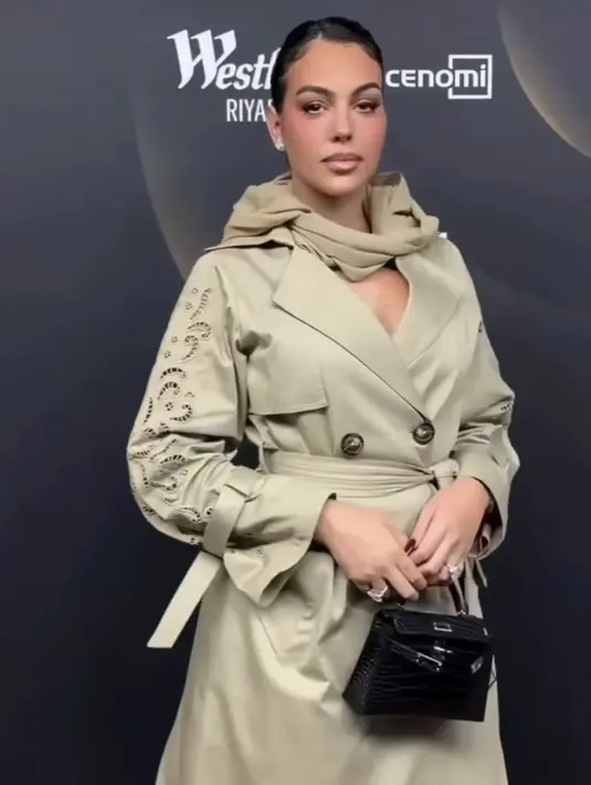 Hadir di fashion show, tunangan pesepak bola Cristiano Ronaldo pun tampil dengan nuansa eartone. Ia mengenakan long coat dress dengan aksen kancing depan dan belt. [@georginagio]