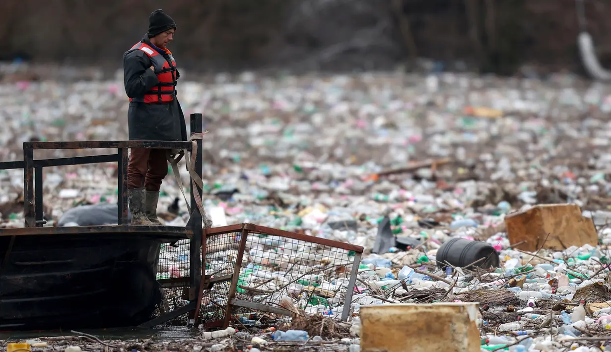 Pekerja perusahaan utilitas mendorong limbah ke tepi Sungai Lim dekat Priboj, Serbia, 30 Januari 2023. Botol plastik, papan kayu, tong berkarat, dan sampah lainnya dari tempat pembuangan sampah tepi sungai yang tidak diatur dengan baik terakumulasi selama air pasang. (AP Photo/Armin Durgut)