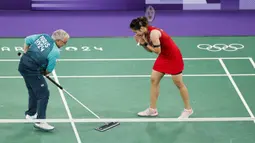 Seorang volunter sedang memberishkan keringan pebulu tangkis putri Thailand, Ratchanok Intanon saat pertandingan grup Olimpiade Paris 2024 melawan atlet Belgia, Lianne Tan di Porte de la Chapelle Arena, Paris, Prancis pada 30 Juli 2024. (AFP/Luis Tato)