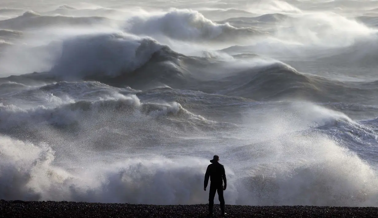 Seseorang melihat ke arah ombak yang menerjang pantai di Newhaven pada tanggal 2 Januari 2024. (ADRIAN DENNIS/AFP)