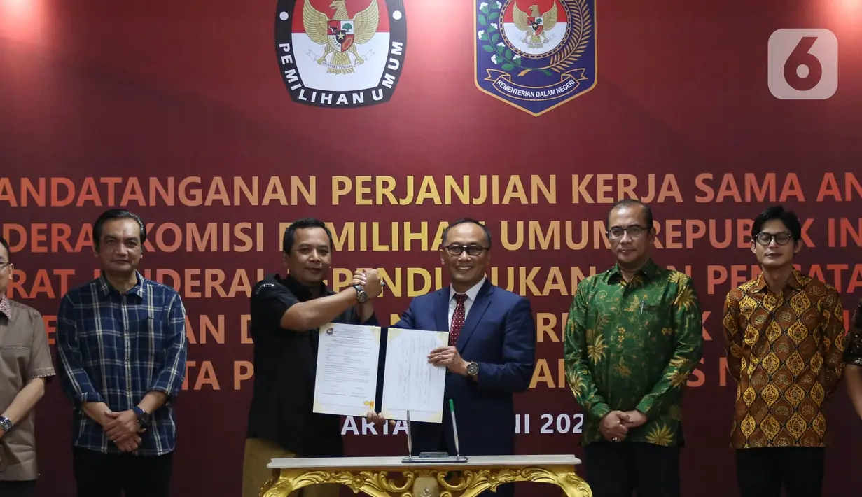 Sekretaris Jenderal KPU RI Bernad Dermawan Sutrisno (ketiga kiri) bersalaman dengan dengan Dirjen Dukcapil Zudan Arif Fakrulloh (ketiga kanan) disaksikan Ketua KPU RI Hasyim Asy'ari (kedua kanan) saat penandatanganan perjanjian kerja sama antara Direktur Jenderal Dukcapil Kemendagri dengan Sekretaris Jenderal KPU RI di Gedung KPU, Jakarta, Rabu (29/6/2022). Kerja sama ini mengenai pemanfaatan nomor induk kependudukan, data kependudukan, dan kartu tanda penduduk elektronik dalam pemutakhiran data pemilih. (Liputan6.com/Angga Yuniar)