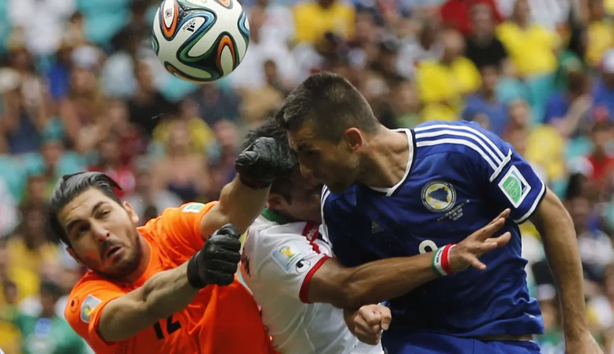 Penjaga gawang Iran, Alireza Haghighi (kiri), berusaha menahan sundulan kepala pemain depan Bosnia, Vedad Ibisevic, di laga penutup penyisihan Piala Dunia 2014 Grup F di Stadion Fonte Nova, Salvador, Brasil, (25/6/2014). (REUTERS/Sergio Perez)