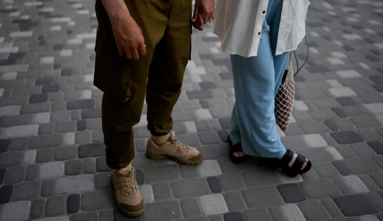 Komika Serhiy Lipko dan Anastasia Zukhvala bergandengan tangan saat wawancara dengan The Associated Press pada hari pernikahan mereka di Kyiv, Ukraina, 11 Juni 2022. Lipko mengatakan julukan yang dia gunakan di ketentaraan adalah  "the comedian" dan pandangan komiknya akan membantunya bertahan di medan perang. (AP Photo/Natacha Pisarenko)