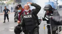 Seorang polisi bereaksi setelah gas air mata dilemparkan selama unjuk rasa anti-pemerintah di Bangkok pada 17 November 2020. (Foto: AFP / Jack Taylor)