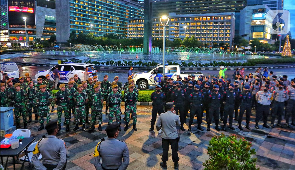 Personel gabungan TNI-Polri saat apel persiapan pengamanan perayaan malam Tahun Baru 2023 di Bundaran HI, Jakarta, Sabtu (31/12/2022). Tim gabungan TNI-Polri merapatkan barisan untuk berkoordinasi menjaga acara puncak malam tahun baruan di Bundaran HI. (Liputan6.com/Angga Yuniar)