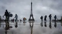 Pengunjung berjalan di Esplanade du Trocadero dengan latar belakang Menara Eiffel, yang ditutup untuk umum pada hari keempat pemogokan stafnya, di Paris pada 22 Februari 2024. (Dimitar DILKOFF/AFP)