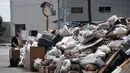 Seorang pria membuang barang-barang yang rusak dari rumahnya usai banjir menerjang Mabi, Prefektur Okayama, Jepang, Rabu (11/7). Hingga kini banjir masih membanjiri sejumlah wilayah di Jepang. (Martin BUREAU/AFP)