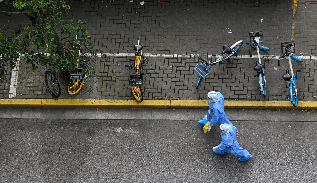 Petugas kesehatan yang mengenakan alat pelindung diri (APD) berjalan di jalan saat lockdown akibat virus corona COVID-19 di Distrik Jing'an, Shanghai, China, Sabtu (16/4/2022). (Hector RETAMAL/AFP)