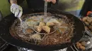 Warga Palestina membuat falafel, makanan yang disukai untuk berbuka puasa, selama bulan suci Ramadhan di pusat kota Hebron di Tepi Barat yang diduduki (9/4/2022). Makanan ini dibuat dari kacang Arab yang digiling dan kemudian dipadatkan dan dibuat bola-bola kecil lalu digoreng. (AFP/Hazem Bader)