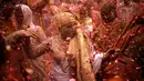 Para janda menari dan saling melempar serbuk berwarna dan kembang saat mengikuti tradisi perayaan Holi di Vrindavan, Uttar Pradesh, India (21/3). Holi merupakan salah satu festival perayaan awal musim semi terbesar di India. (REUTERS/Anindito Mukherjee)